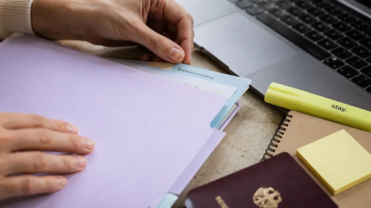 Hands organizing German health insurance switching documents with Stay brand pastel folders and notes.